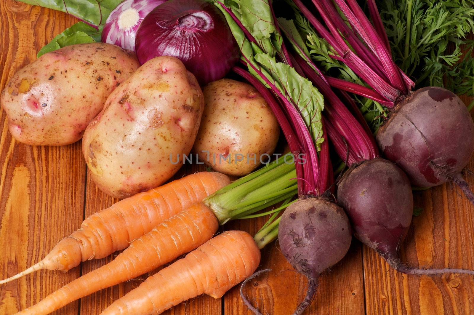 Mix of Raw Organic Farmer's Potato, Carrot, Red Onion and Beet on wooden background