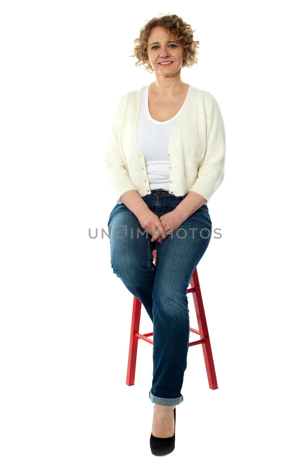 Confident smiling woman sitting on stool and looking at camera