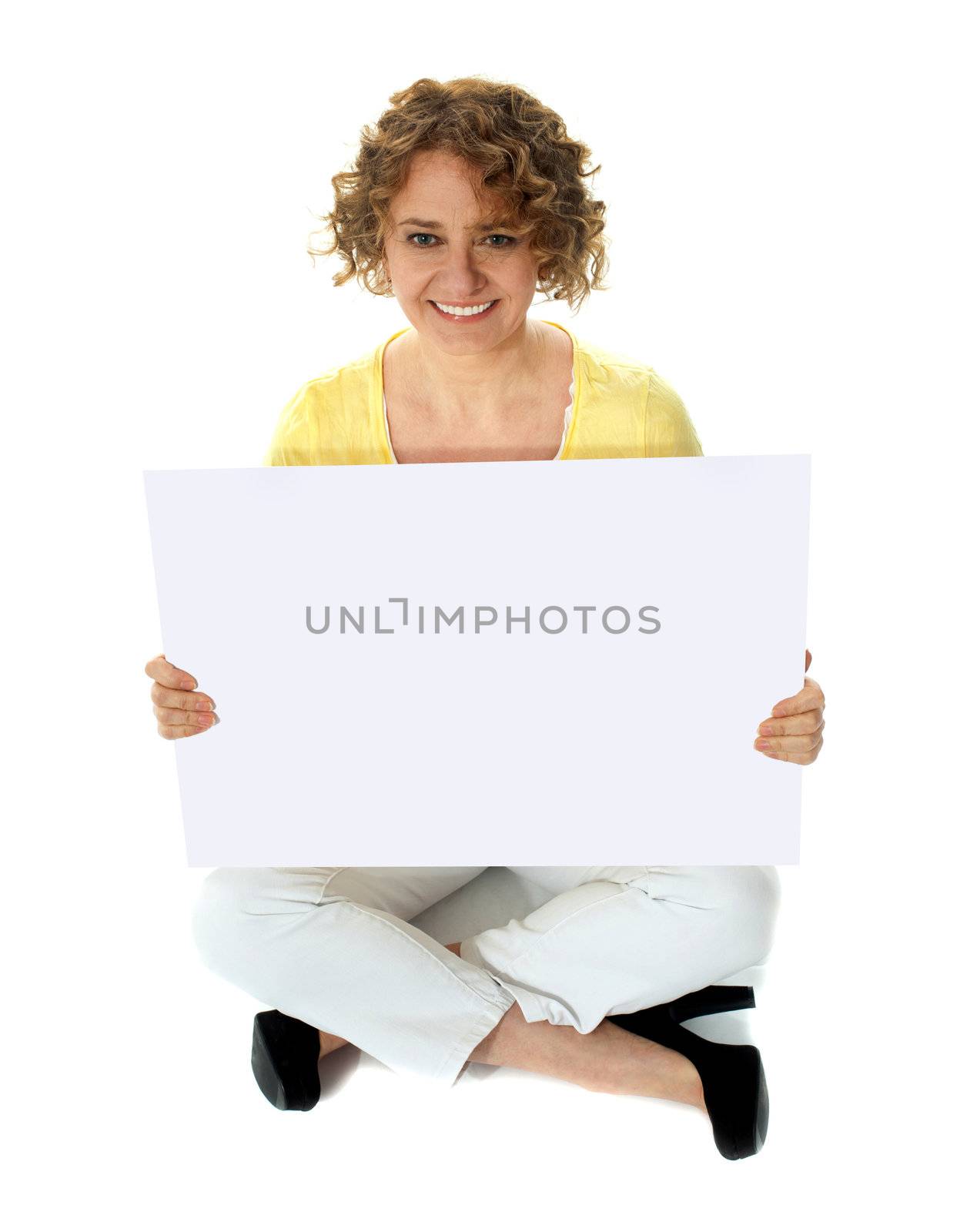 Isolated woman holding blank banner ad sitting on floor. Studio shot