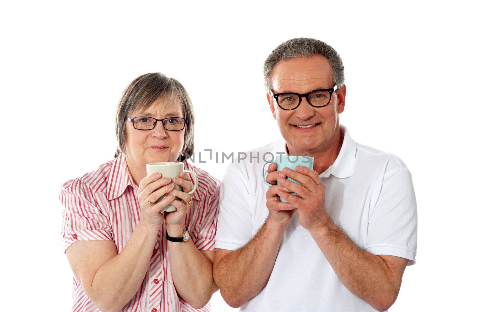 Romantic senior couple holding coffee mugs and smiling at camera