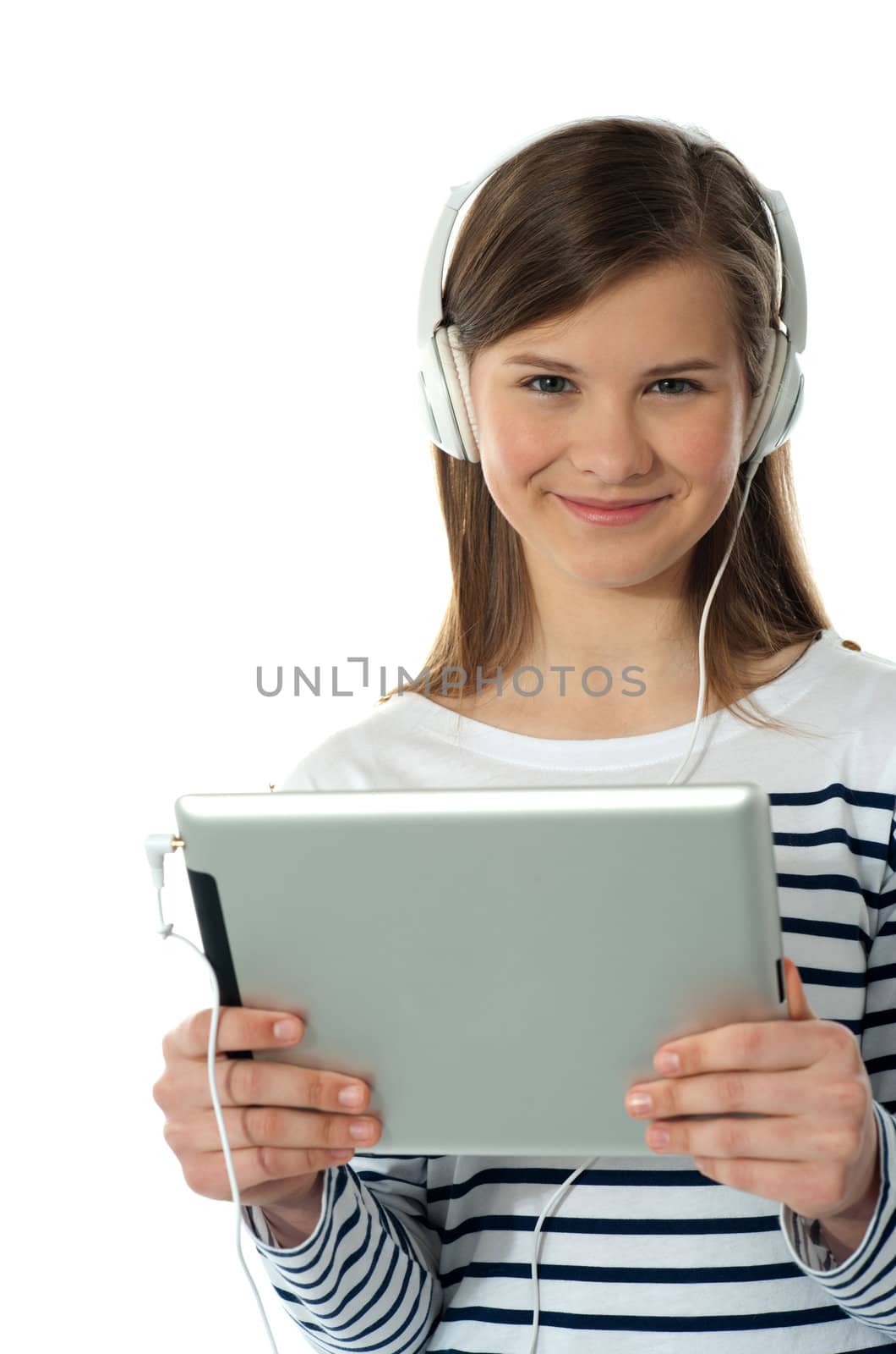 Beautiful girl listening to music via wireless tablet wearing headphones and smiling