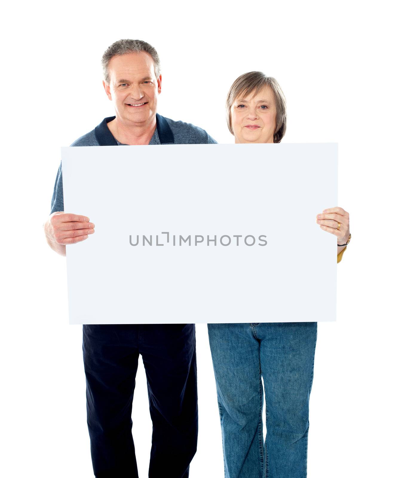 Husband and wife displaying advertising board to camera. Copy space area