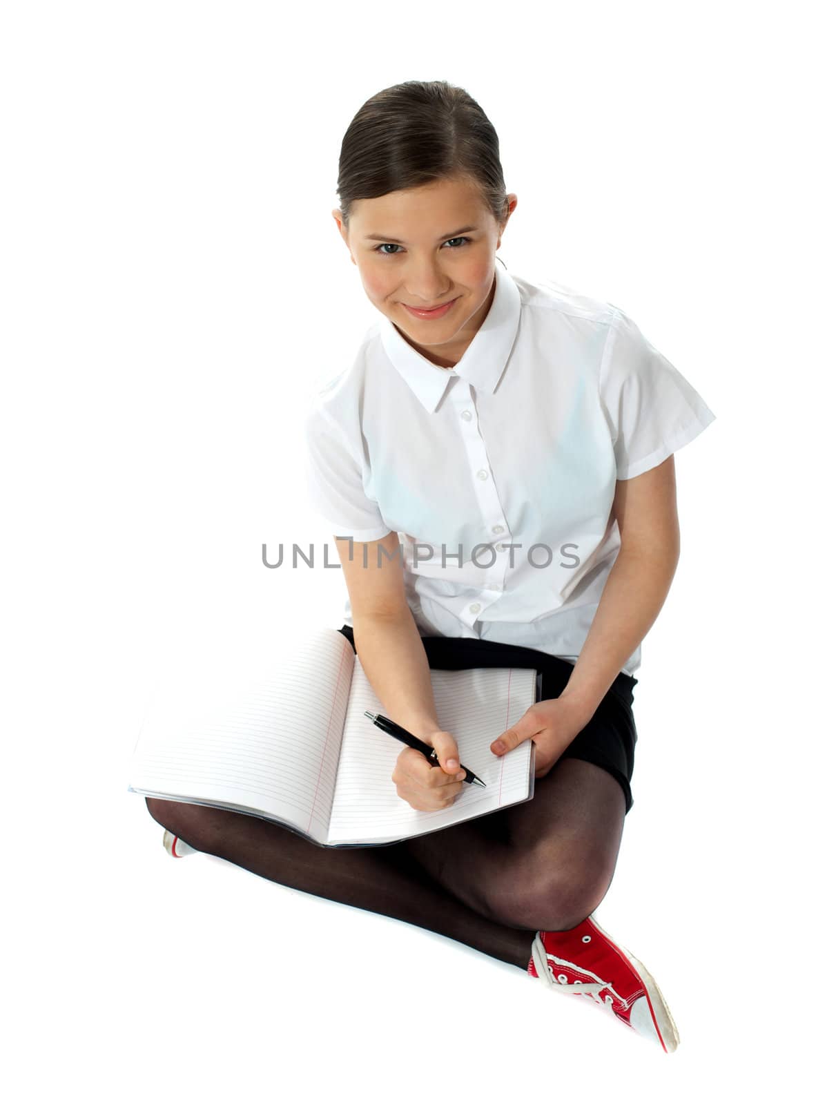 Aerial view of charming schoolgirl doing homework. Isolated on white background