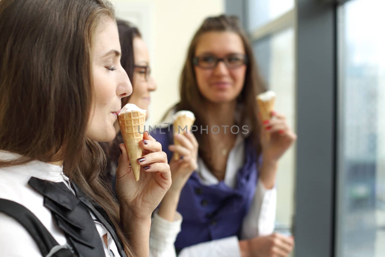 happy smiling women on foreground licking ice cream 