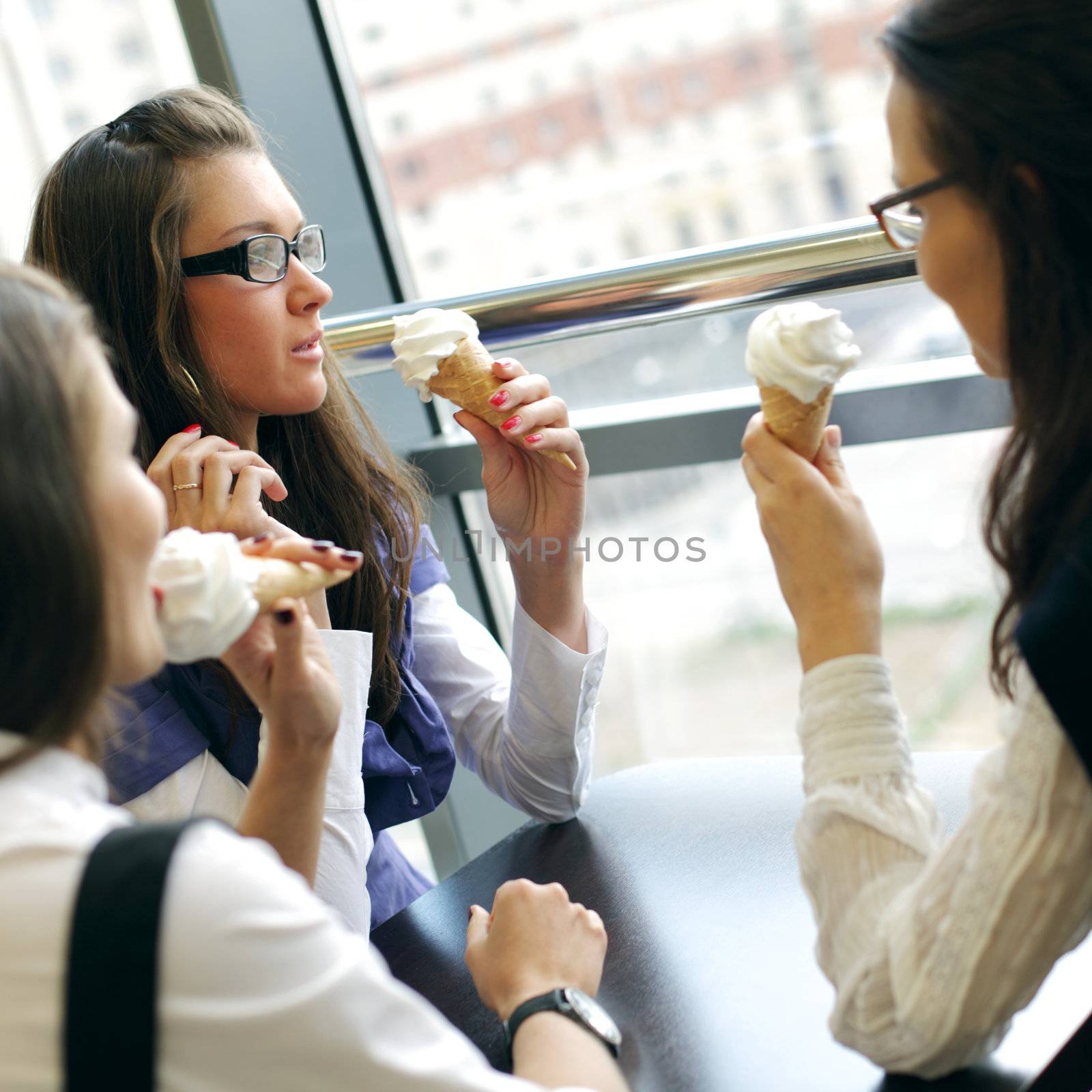 happy smiling women on foreground licking ice cream 