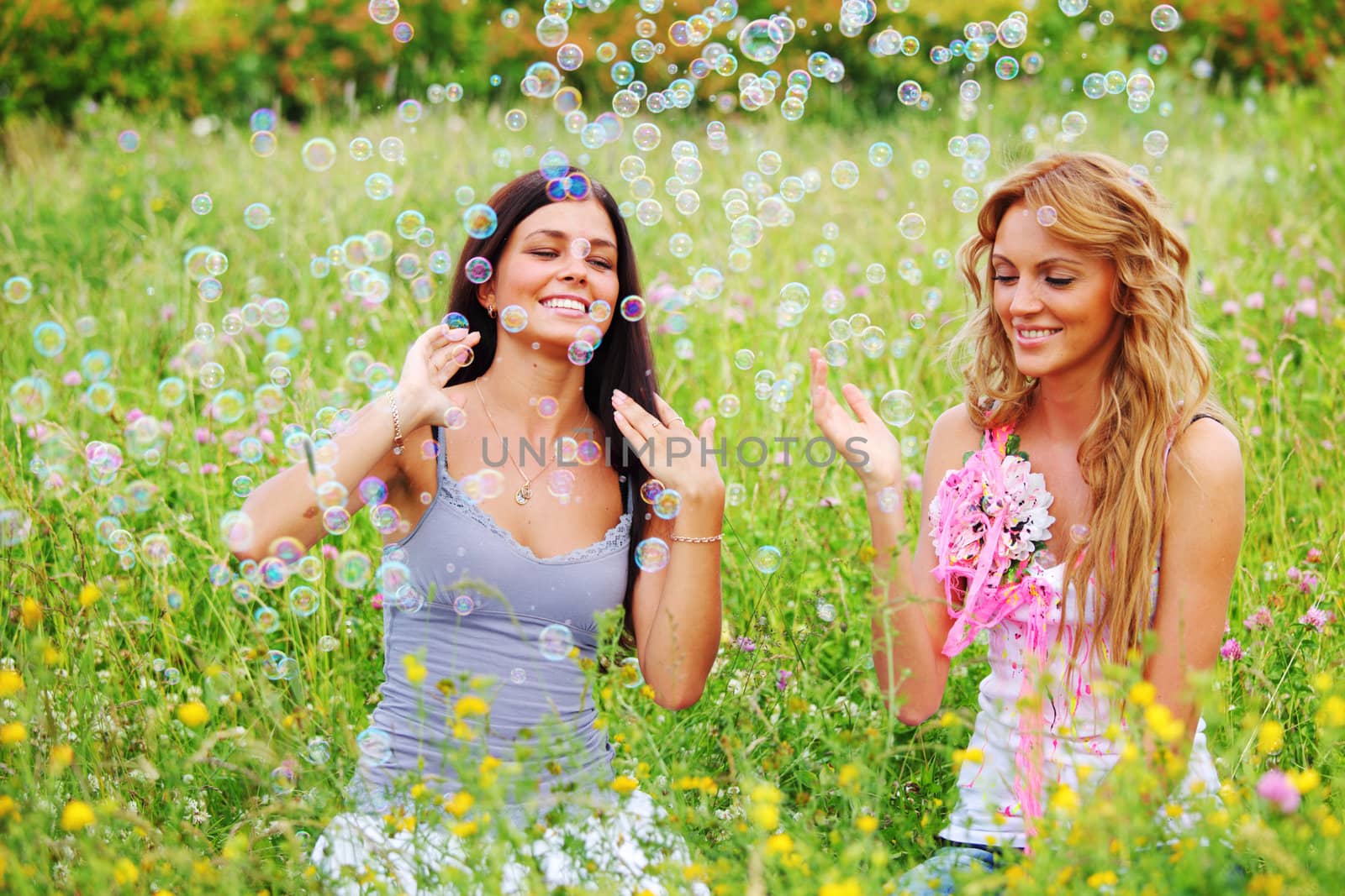 girlfriends on green grass field in soap bubbles