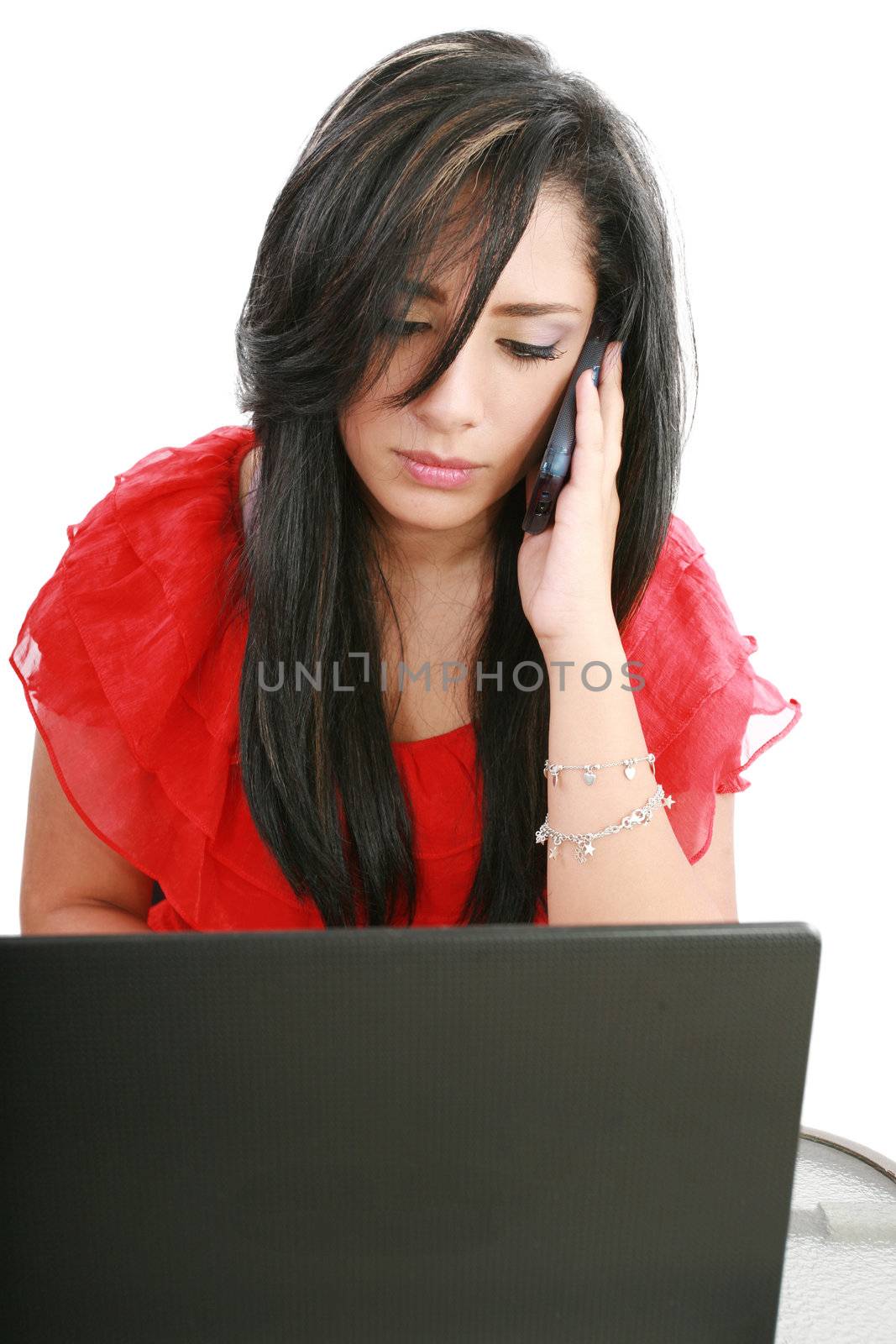 Serious business woman looking at laptop screen while talking on the phone at her work desk, isolated on white background