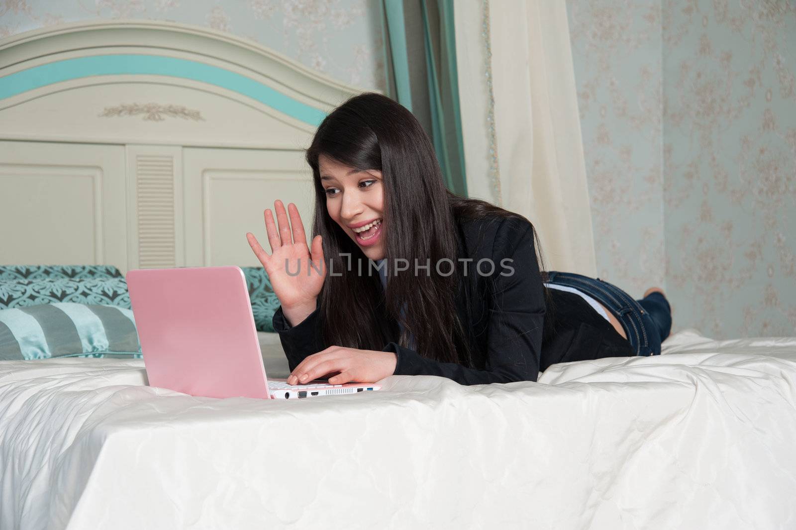 beautiful woman lying in bed having fun talking on Skype