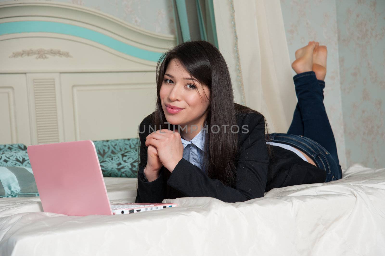beautiful woman lying on the bed with laptop
