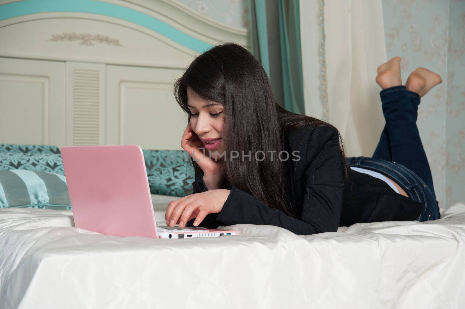  woman lying on the bed with laptop by raduga21