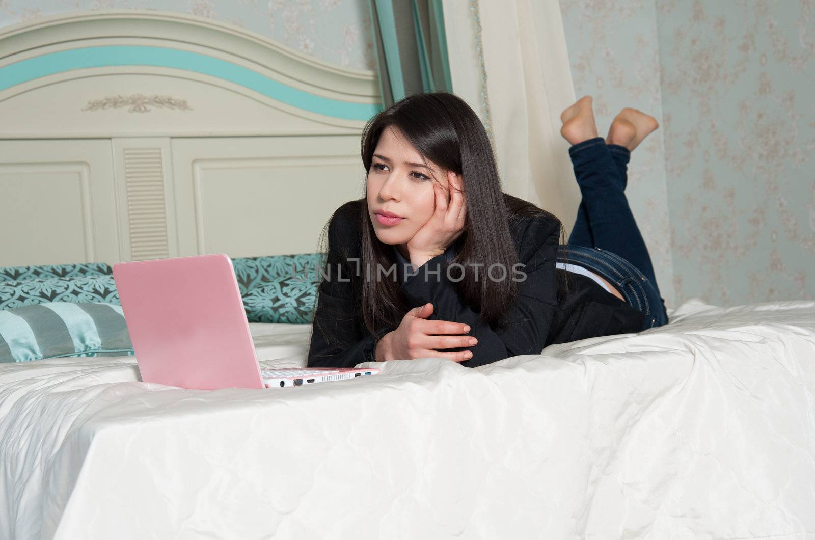  woman lying on the bed with laptop by raduga21