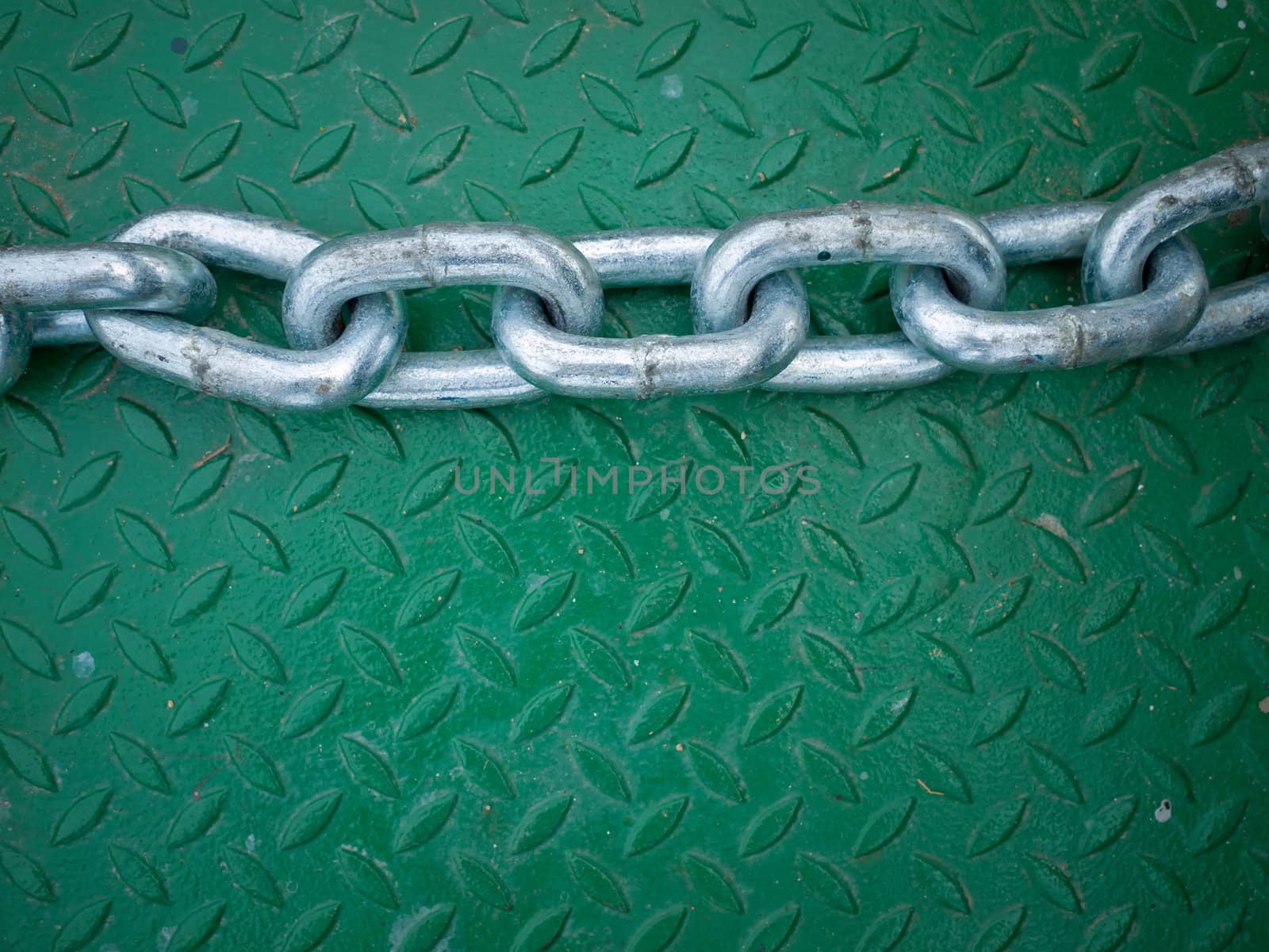 Silver chain on Green Steel Floor Plate by nuttakit