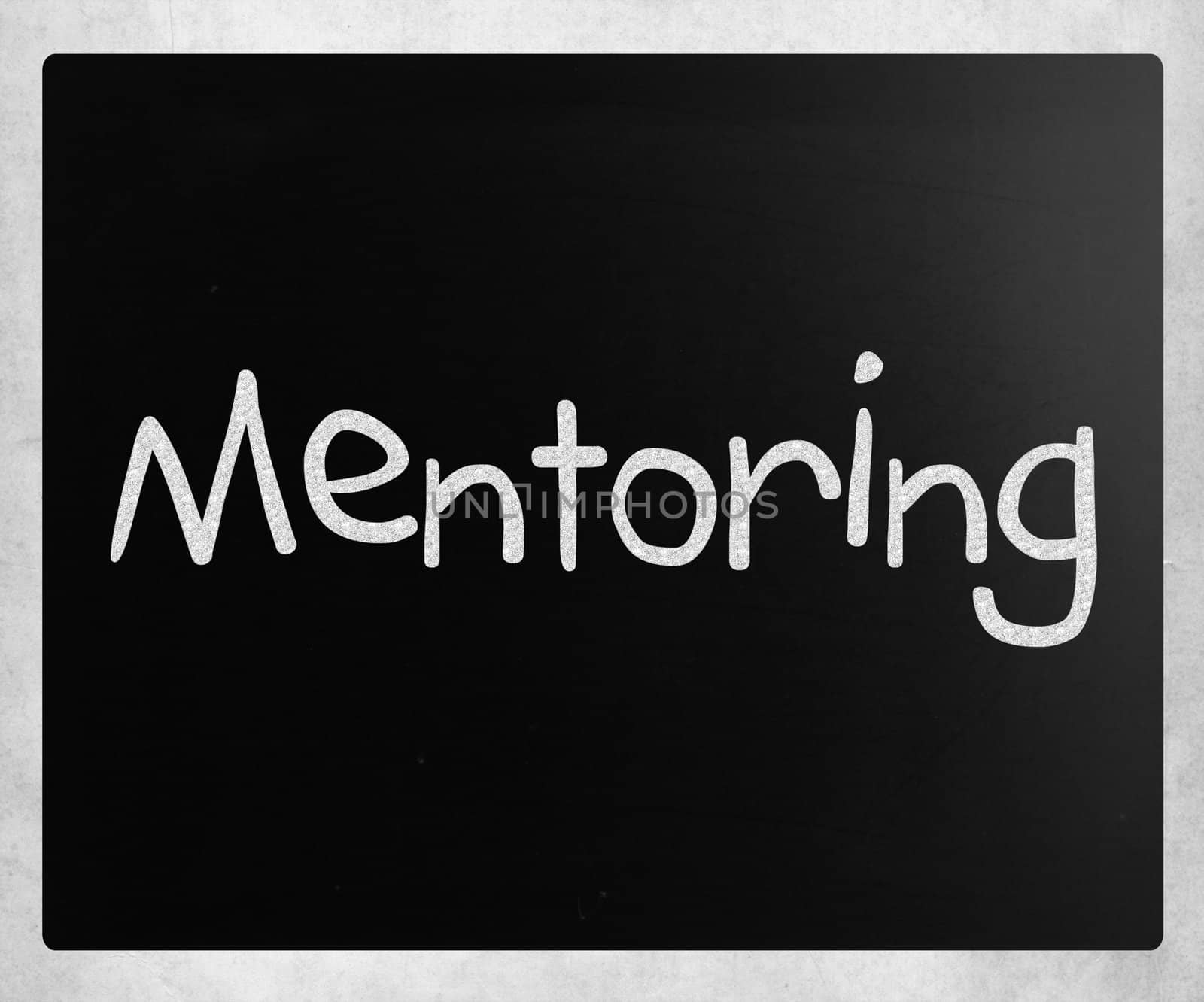 The word "Mentoring" handwritten with white chalk on a blackboard