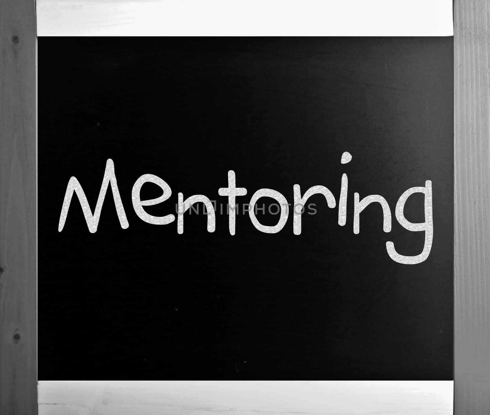 The word "Mentoring" handwritten with white chalk on a blackboard