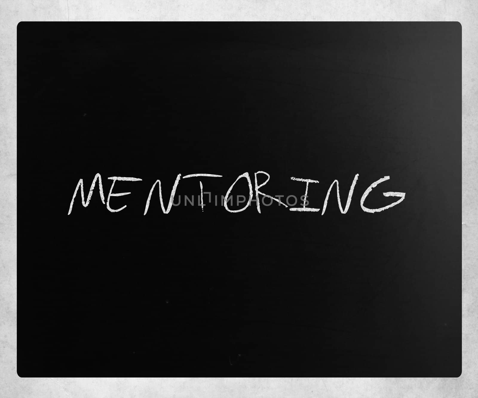 The word "Mentoring" handwritten with white chalk on a blackboard.