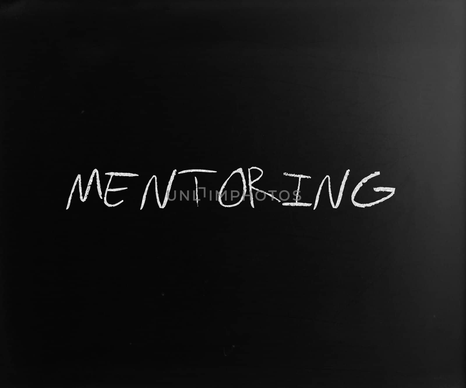 The word "Mentoring" handwritten with white chalk on a blackboard.