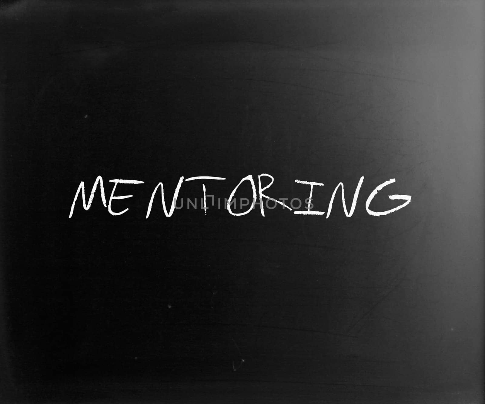 The word "Mentoring" handwritten with white chalk on a blackboard.