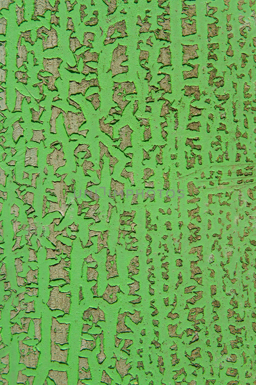 A green painted surface with scratch damageseparating layers of colours.