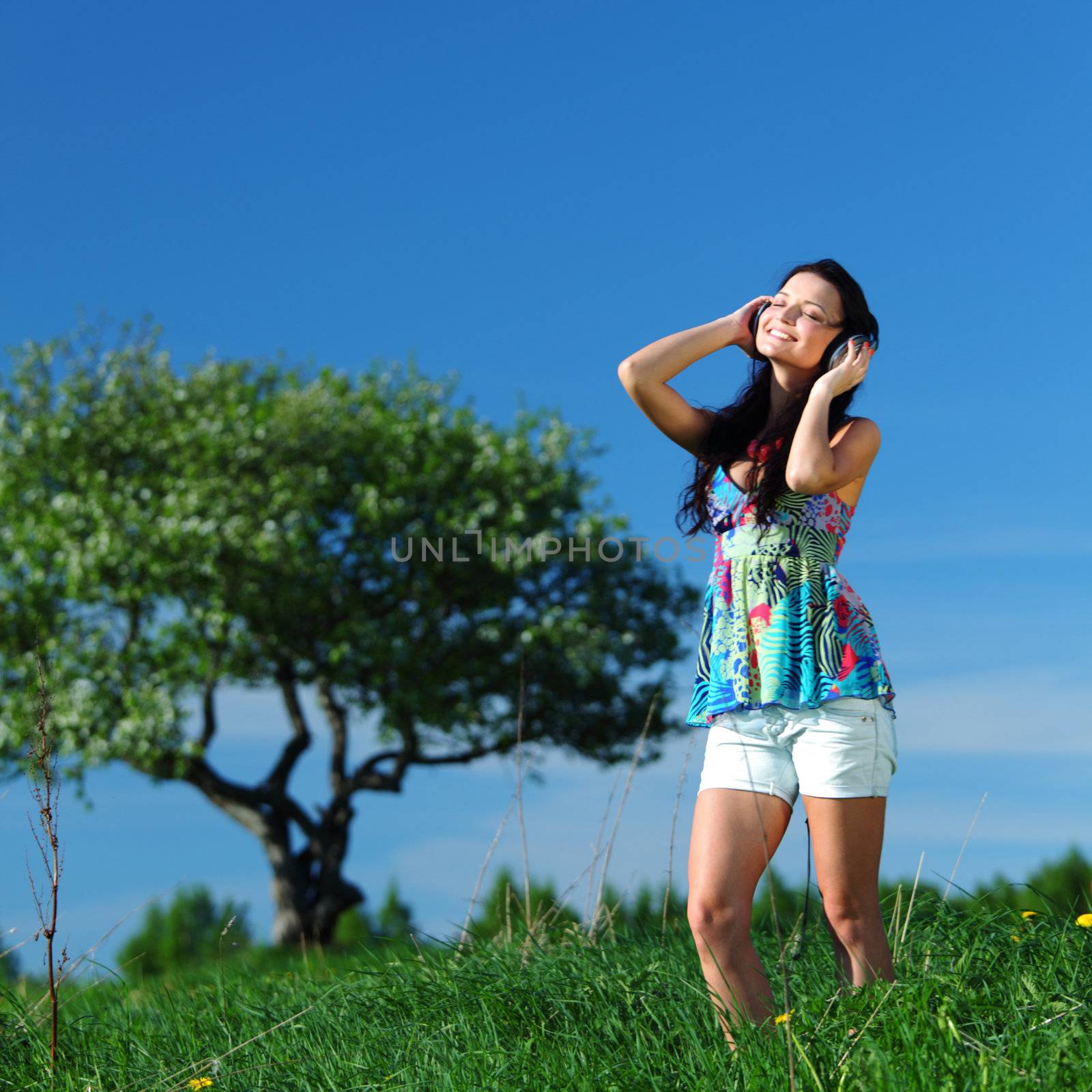 Young woman with headphones listening to music on field