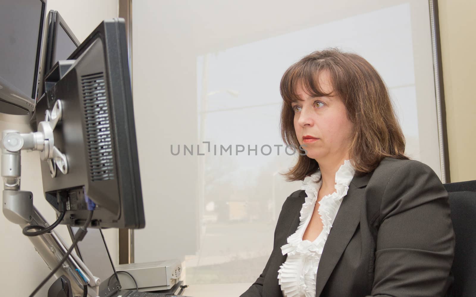 Business woman seated at desk looking at monitor