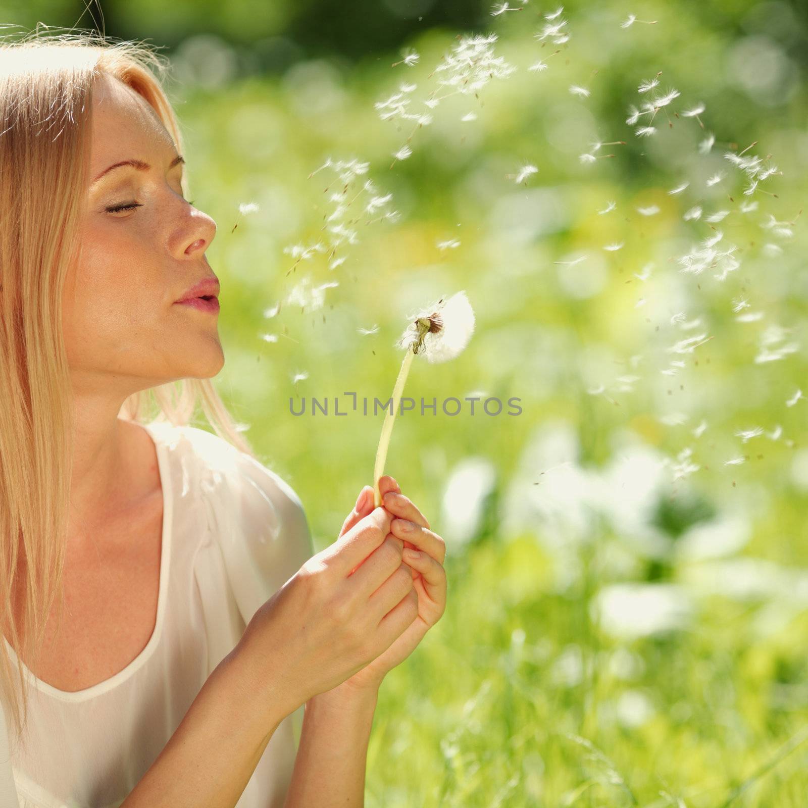 girl blowing on a dandelion lying on the grass