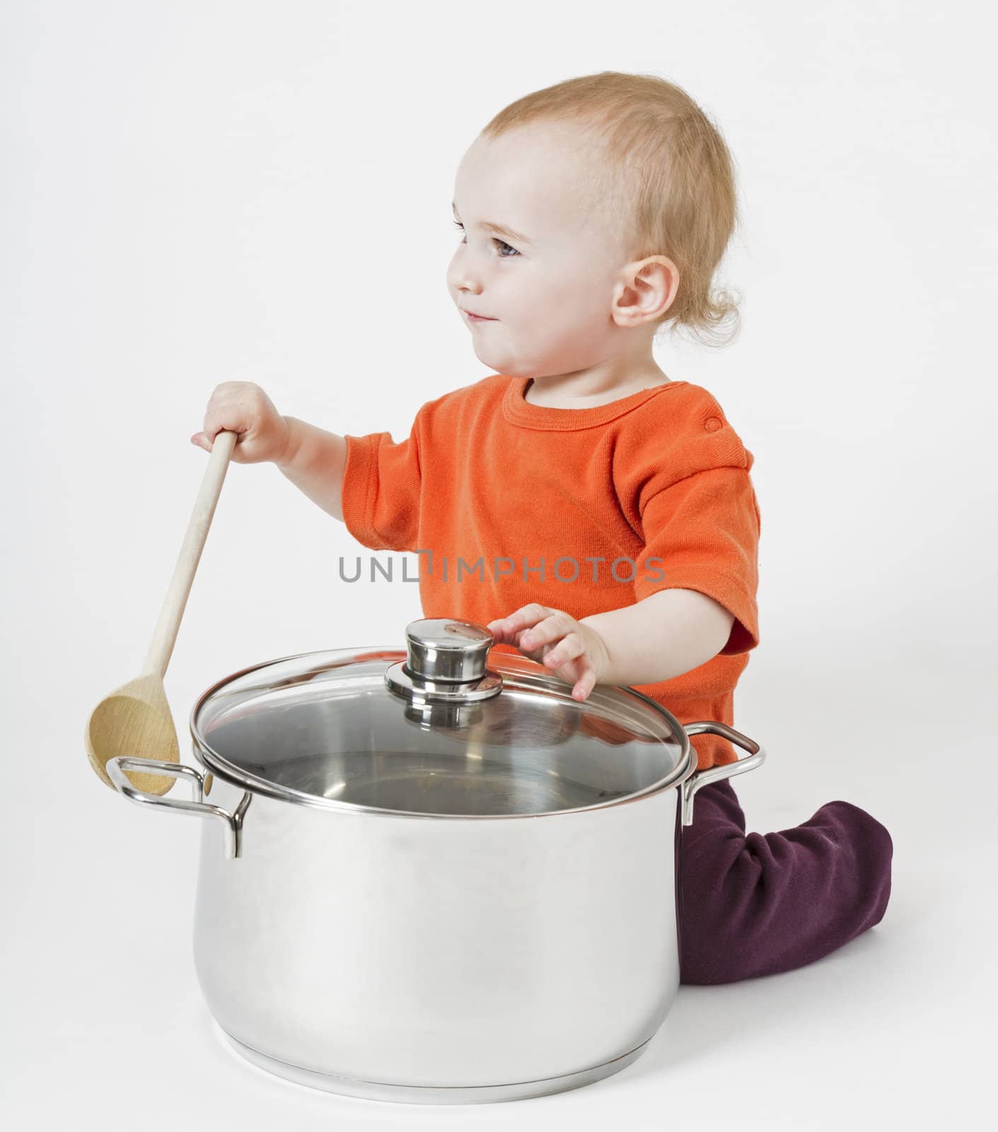 baby with big cooking pot and wooden spoon on neutral background