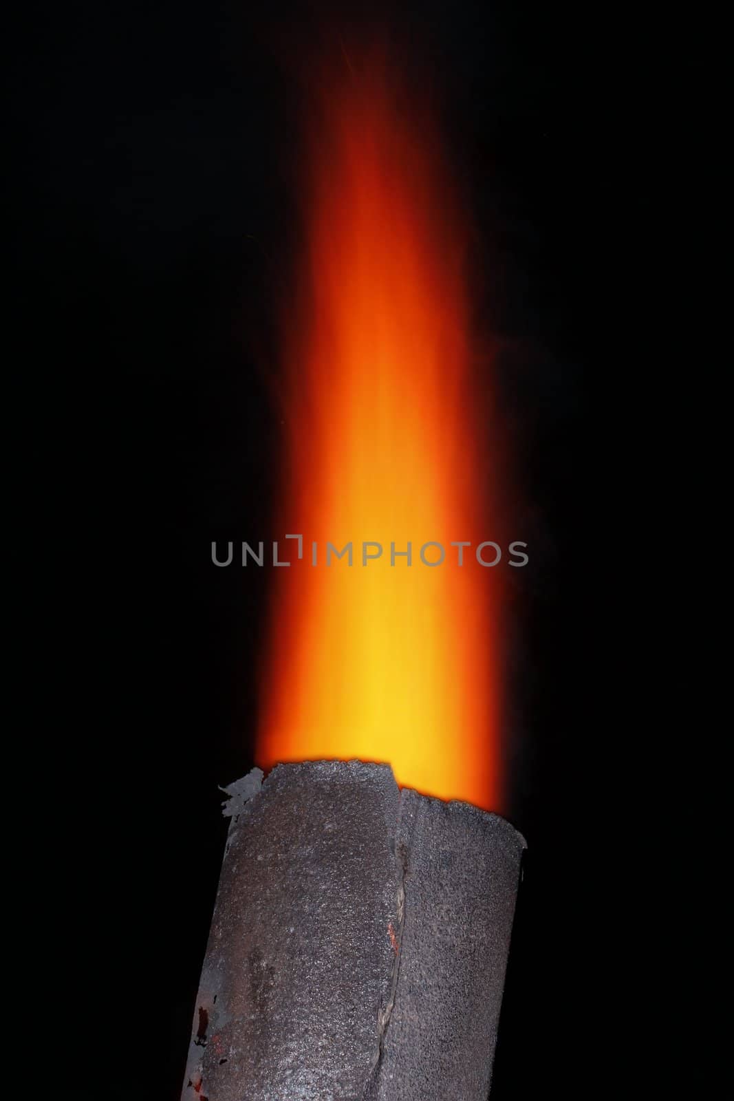 Red torch flame over the old metal chimney at night