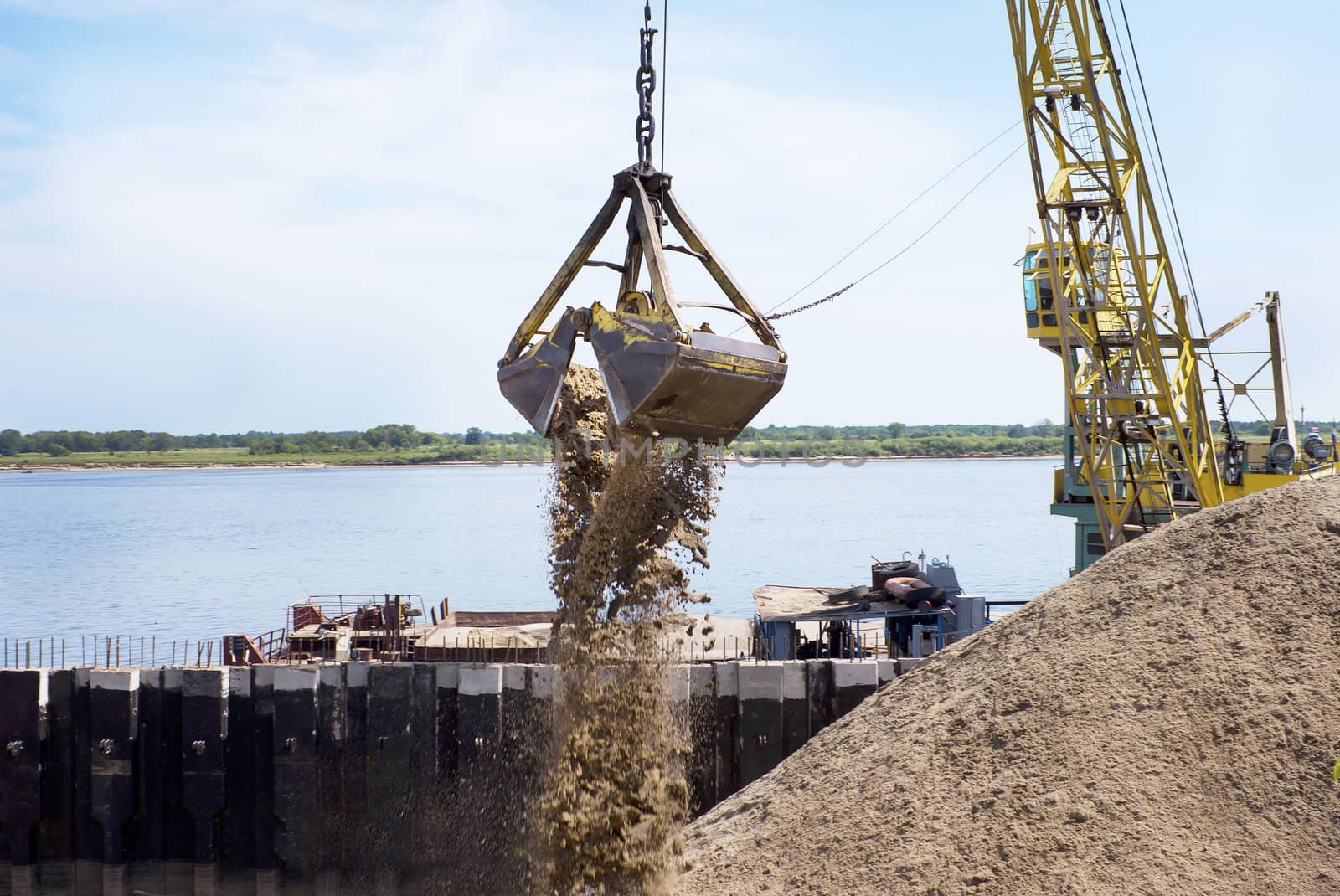 Floating crane scoops soil from the river