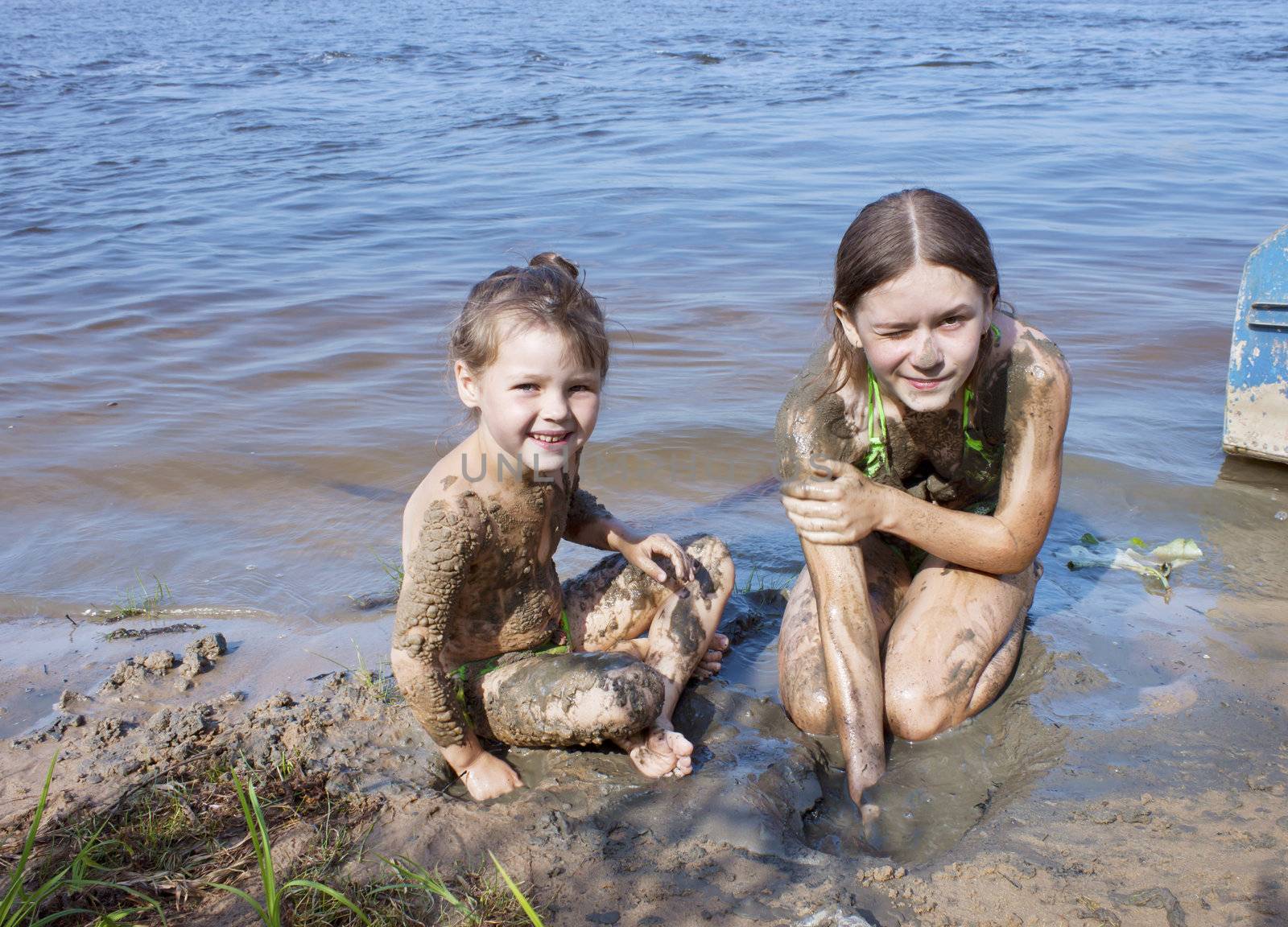 Naughty children in the mud on the river