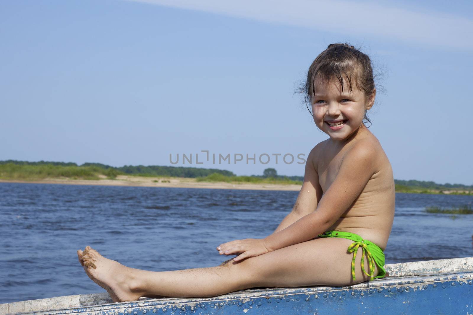 Baby girl sitting on an upturned boat