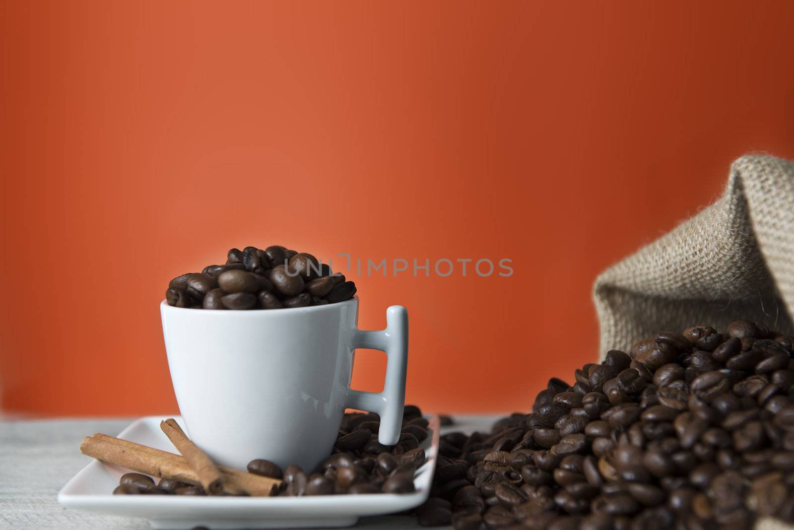 Cup of coffee and beans on an orange vintage background.