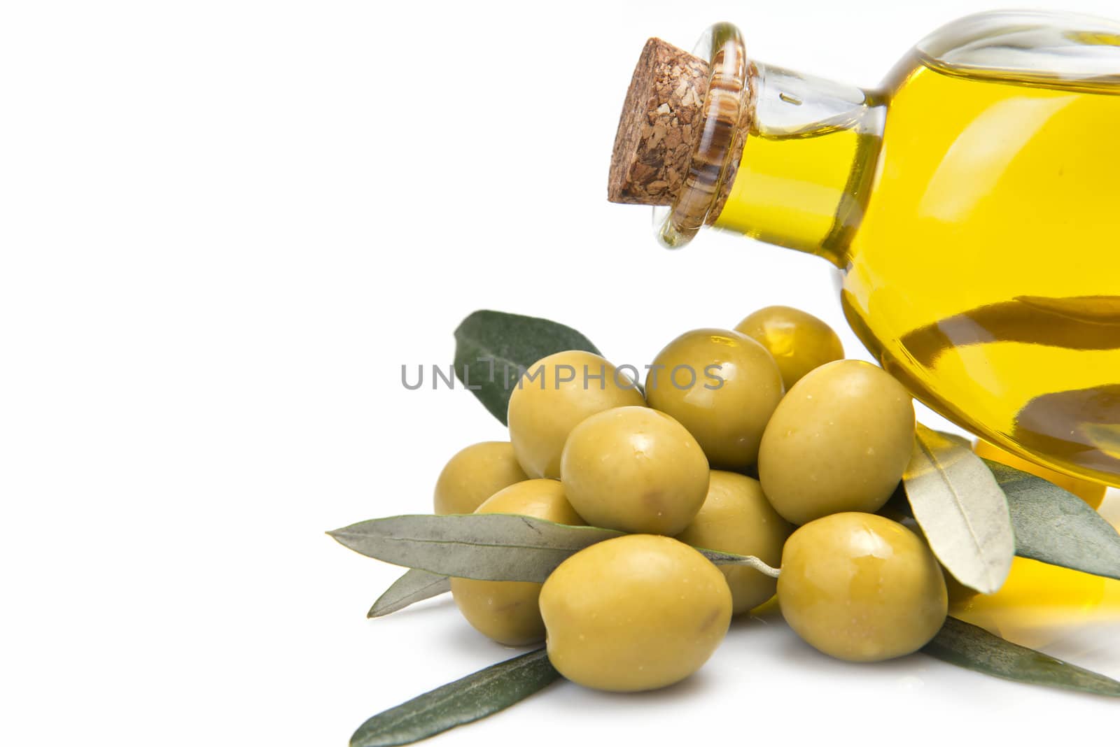 A jar with olive oil and some green olives isolated over a white background.