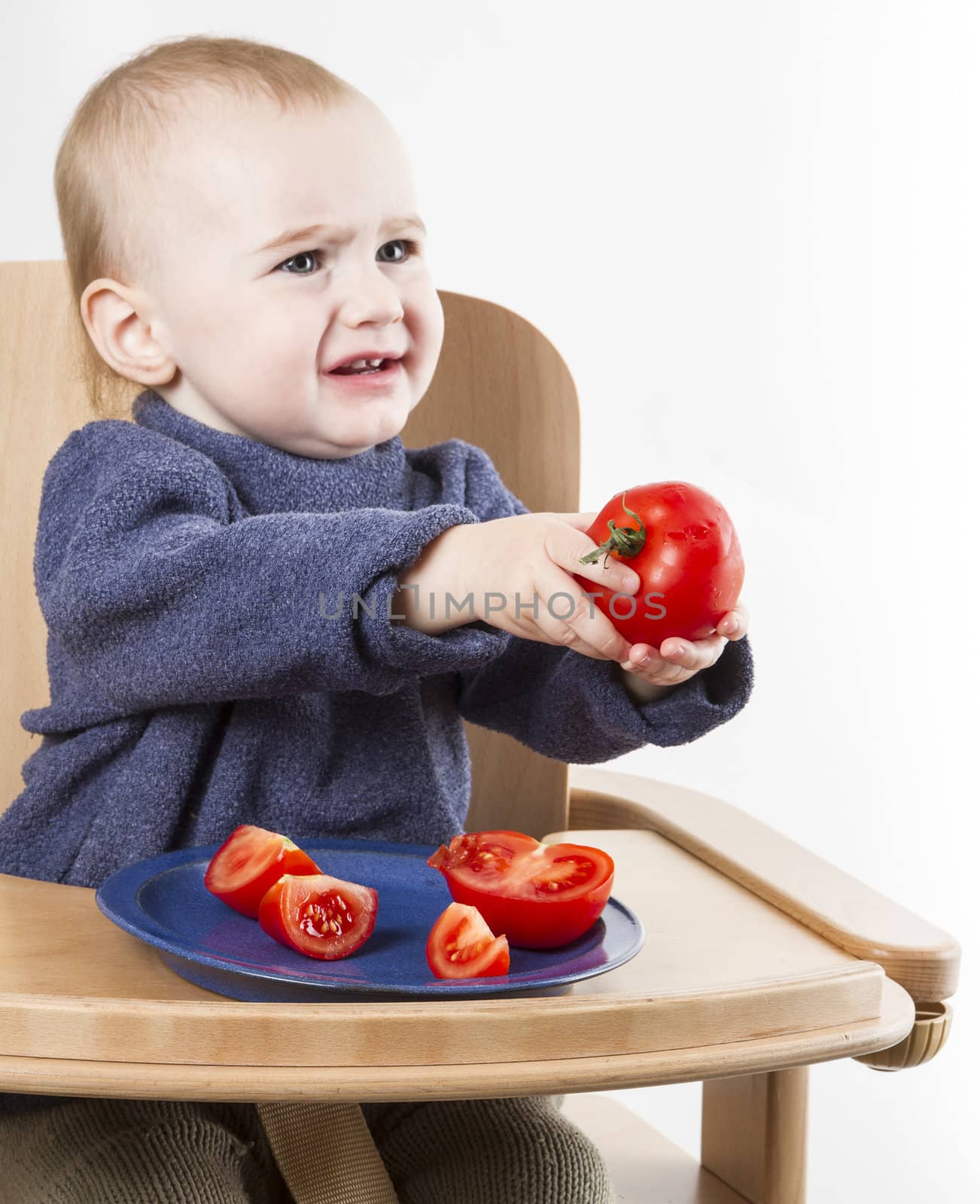 young child eating in high chair isolated in neutral background