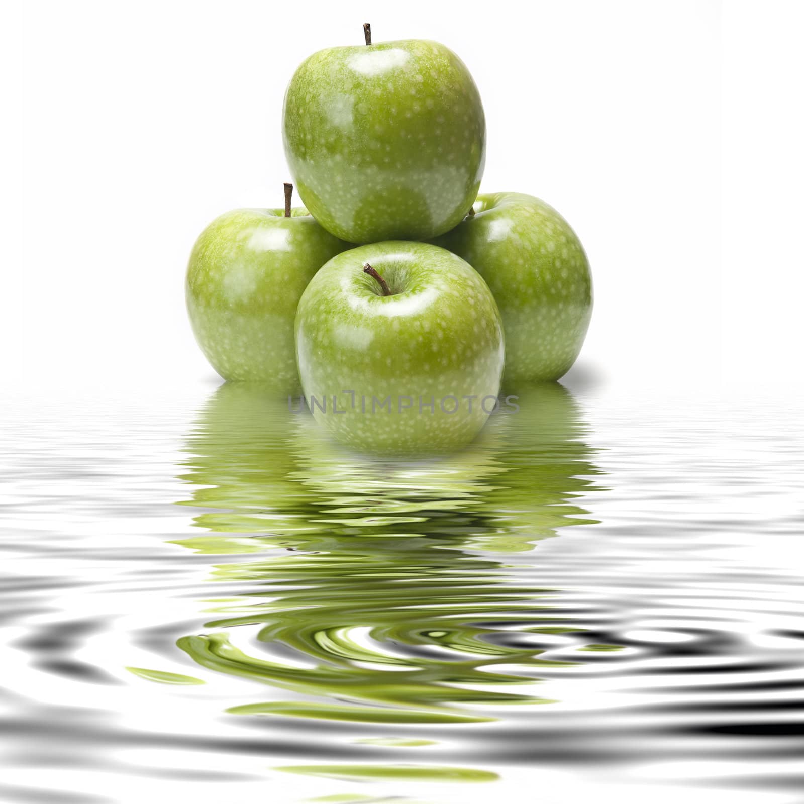 Fresh smith apples reflected on water on a white background.