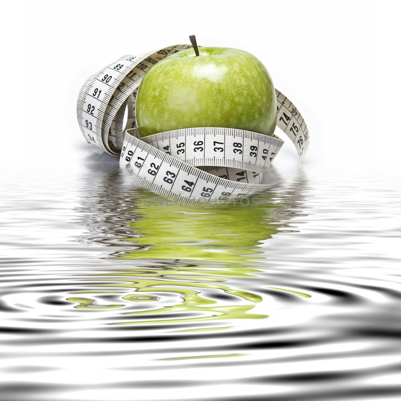 Measuring tape wrapped around a green apple as a symbol of diet.