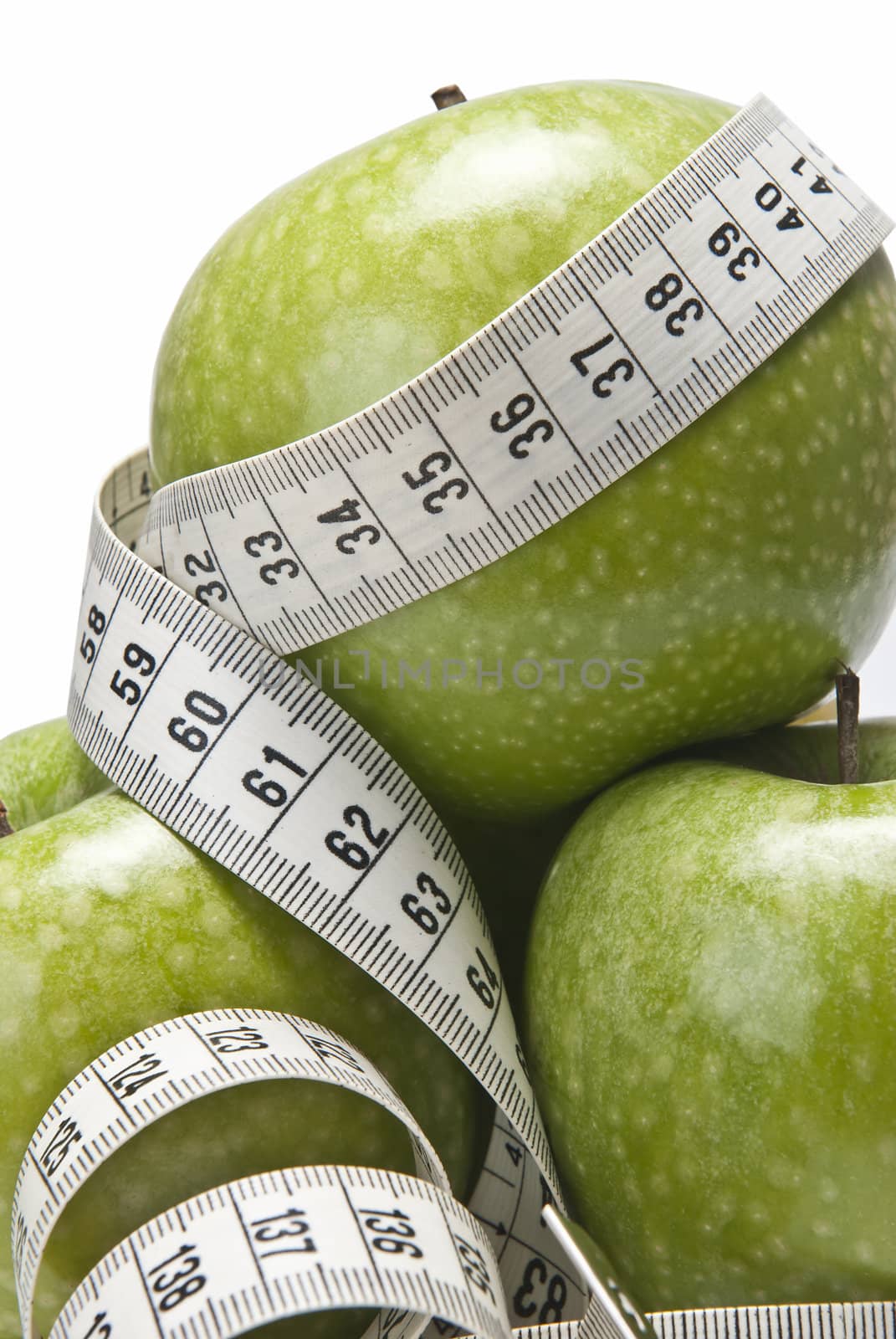 Measuring tape wrapped around a green apple as a symbol of diet.