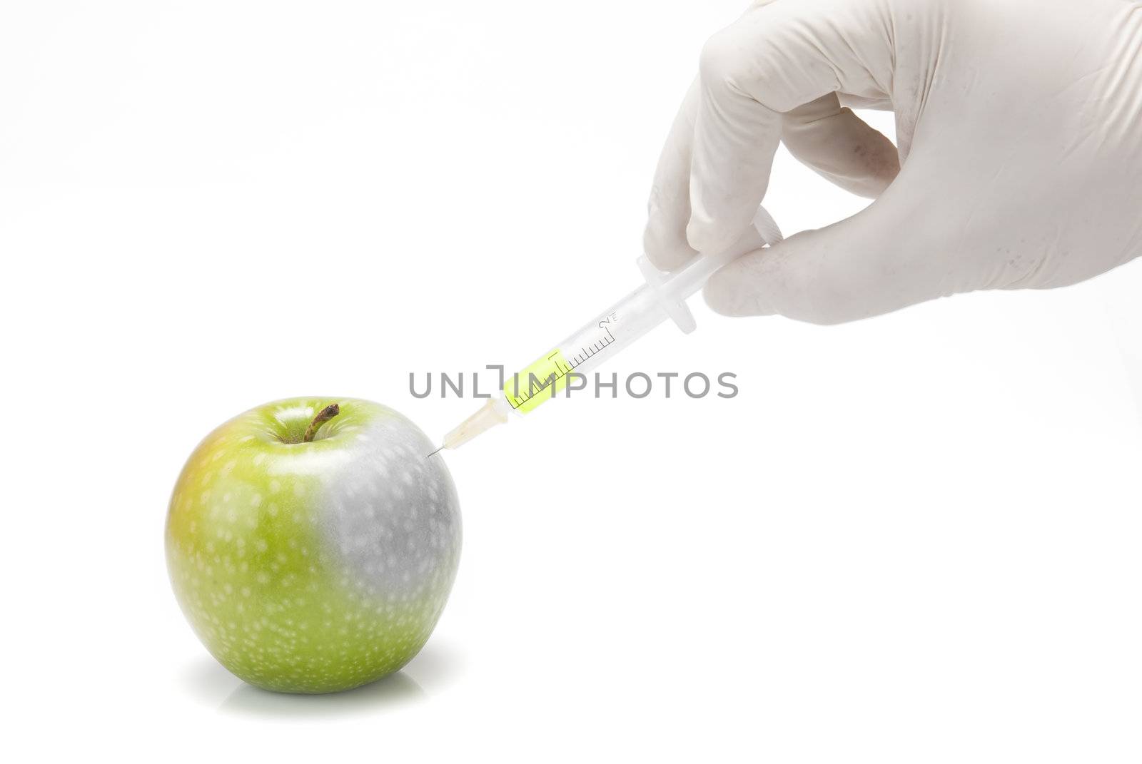 A gloved hand injecting an apple with a syringe on a white background.