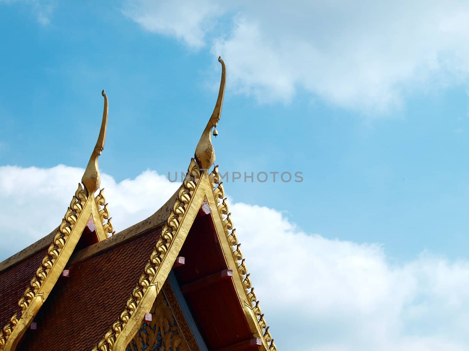 Thai temple roof top decoration in bright blue sky 

