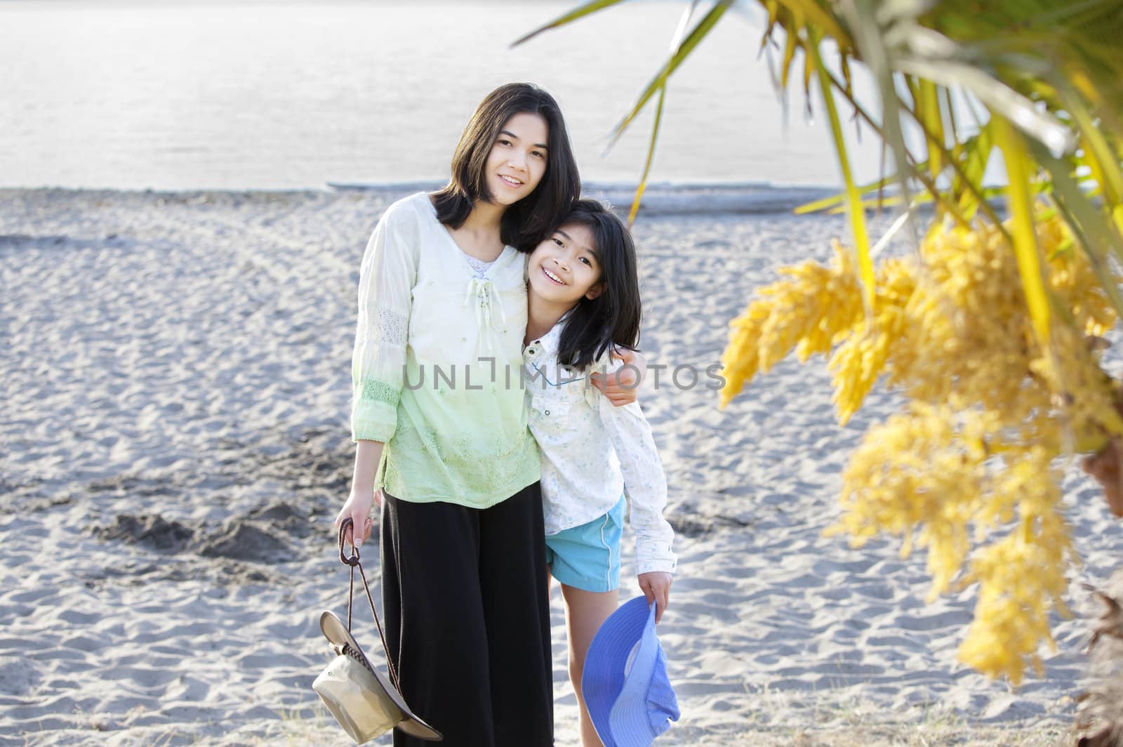 Two beautiful sisters standing on beach together