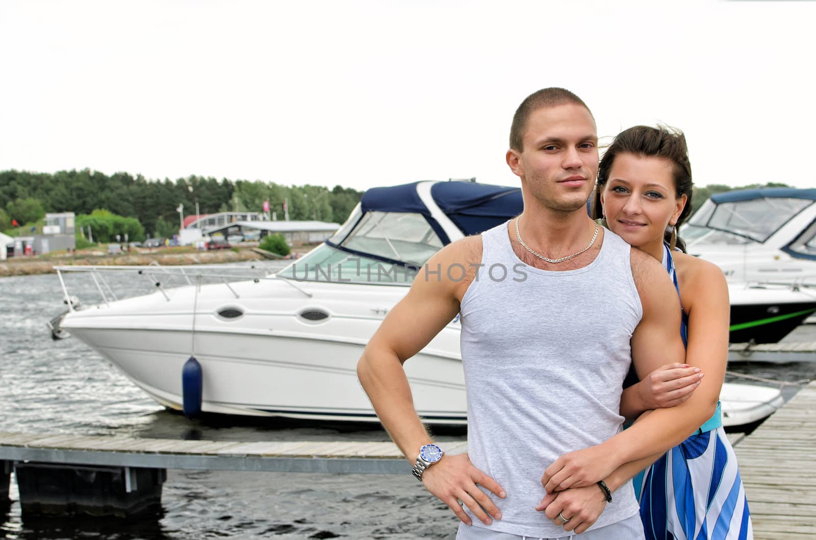 Young couple against pier with boats.