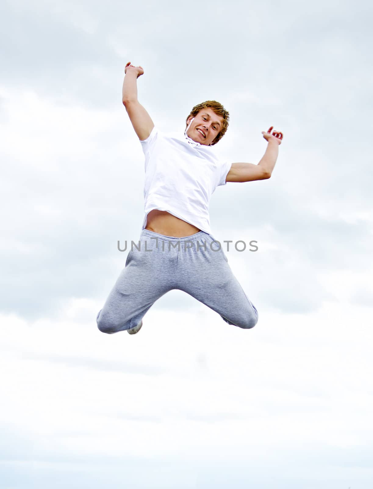 Portrait of a happy young man jumping in air against sky.