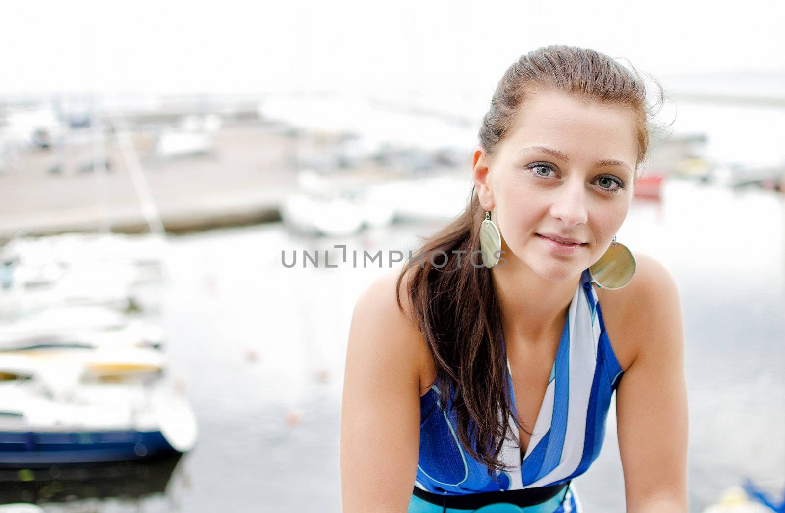 Pretty girl portrait, against of the pier with yachts.