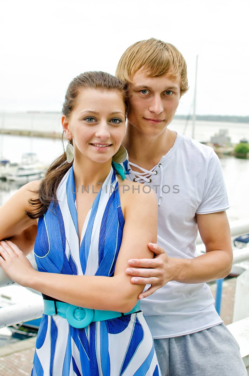 Attractive couple against pier with yachts. by dmitrimaruta