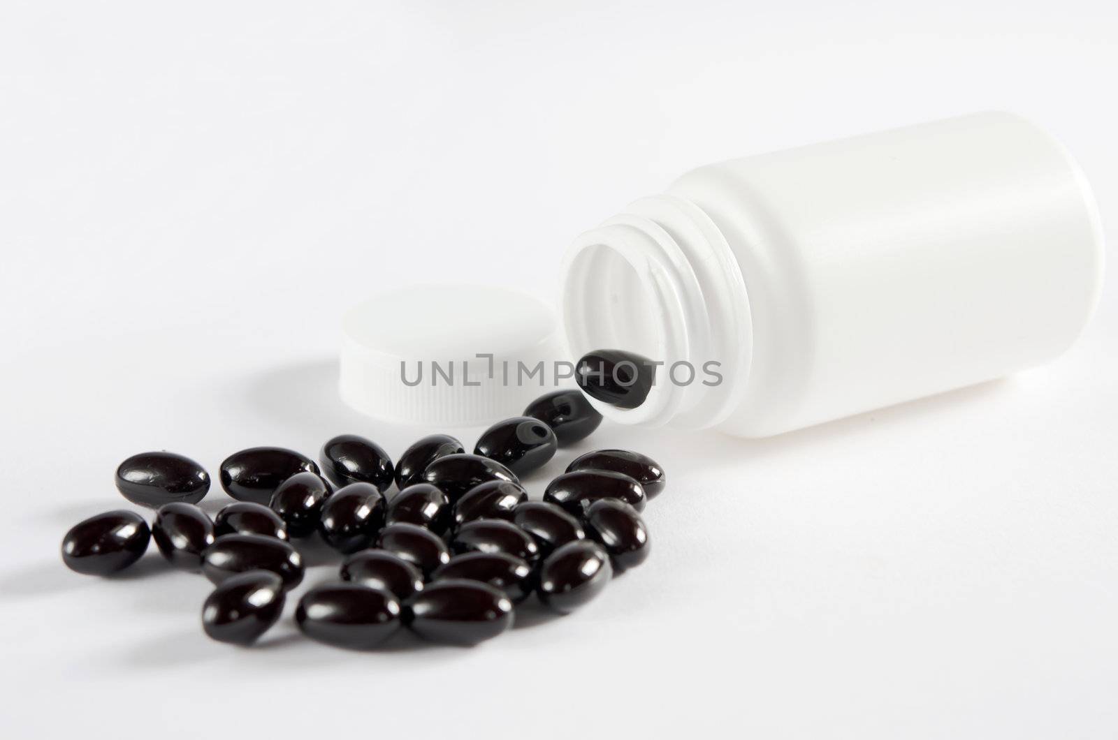 Pills spilling out of  pill bottle on white background