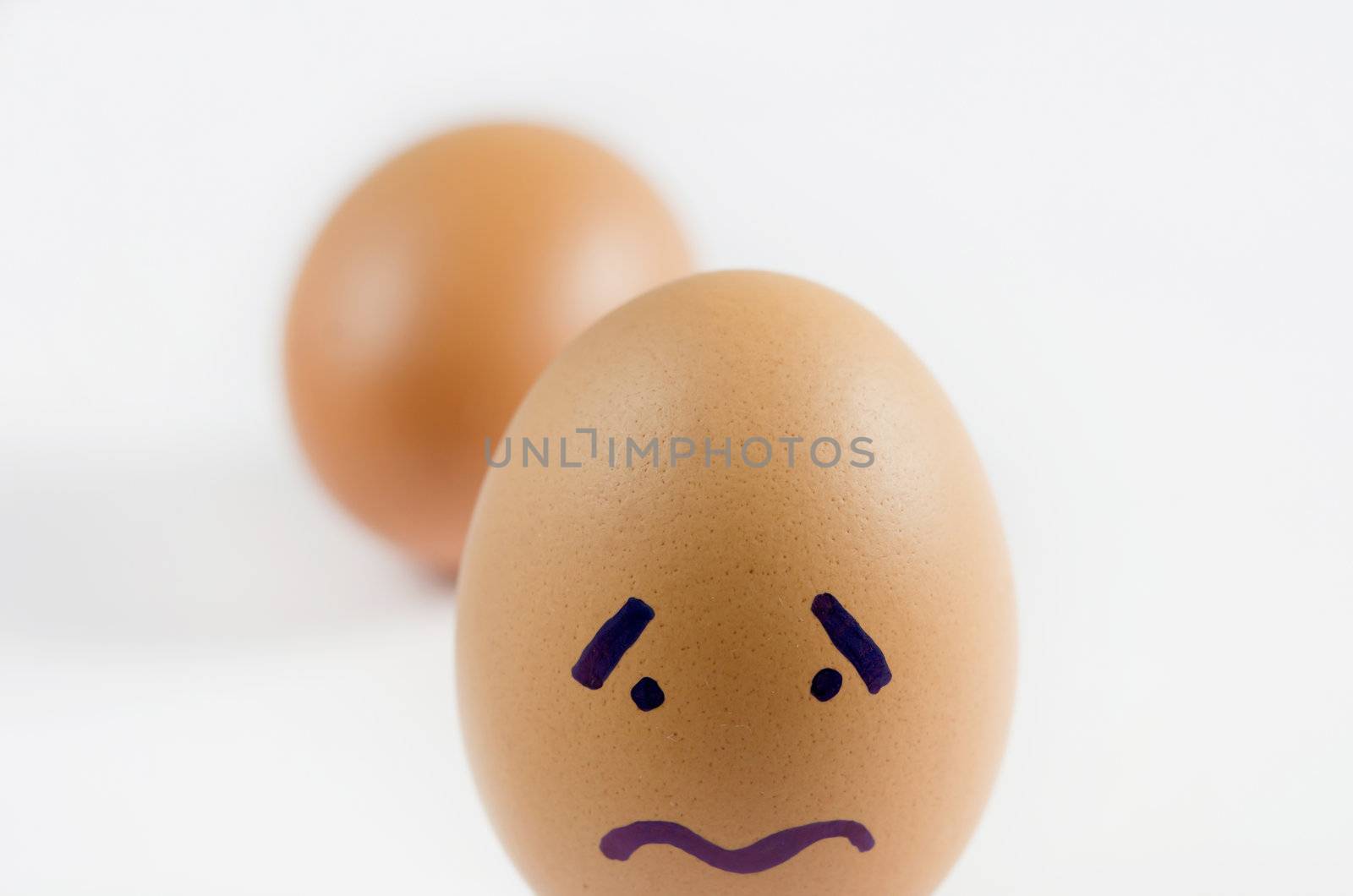 close-up brown eggs with sad face on white background