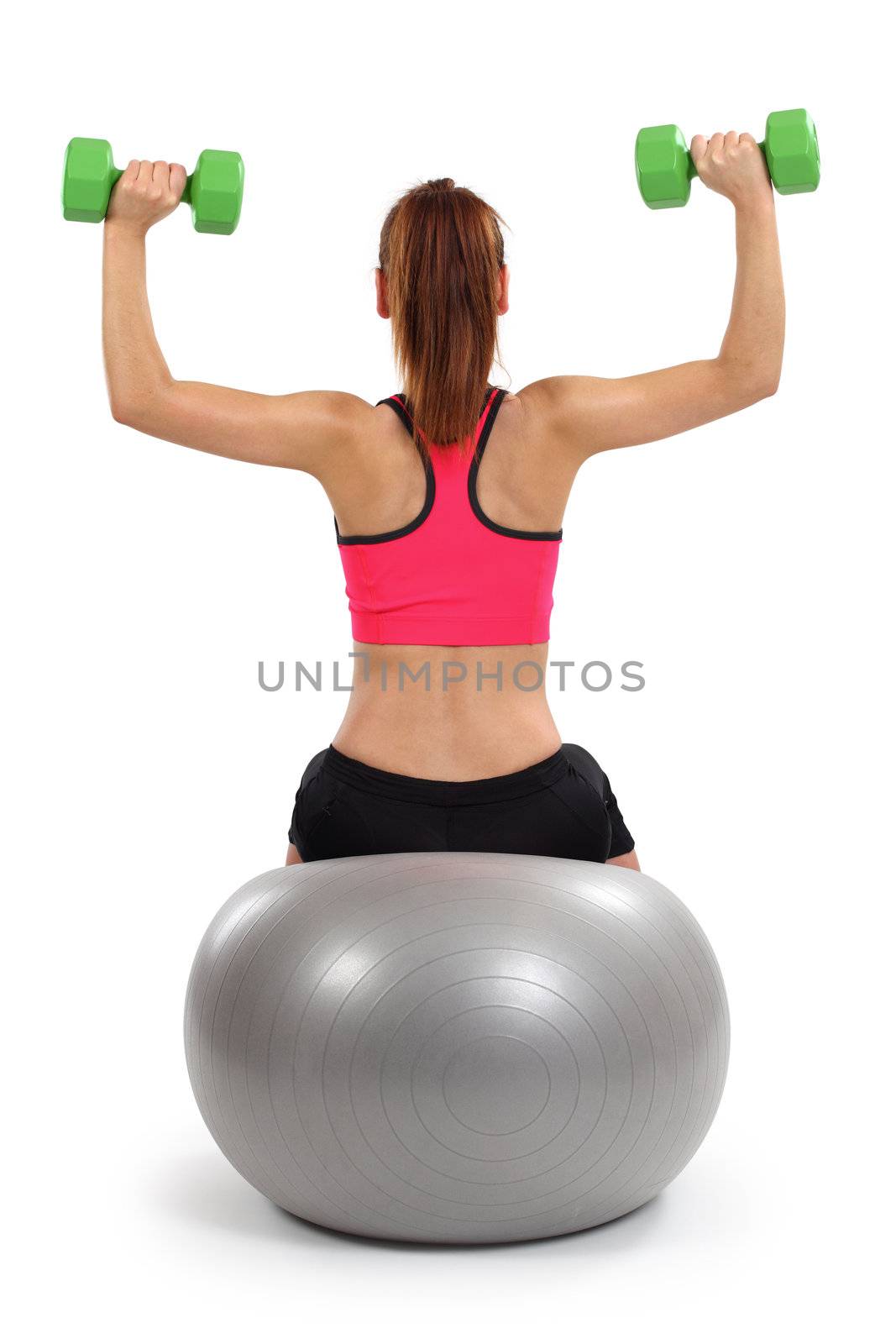 Photo of a female from behind doing dumbbell shoulder press while sitting on an exercise ball.