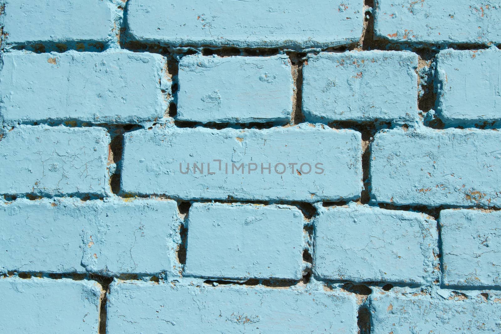 A section of a brick wall painted with a pastel blue colour.