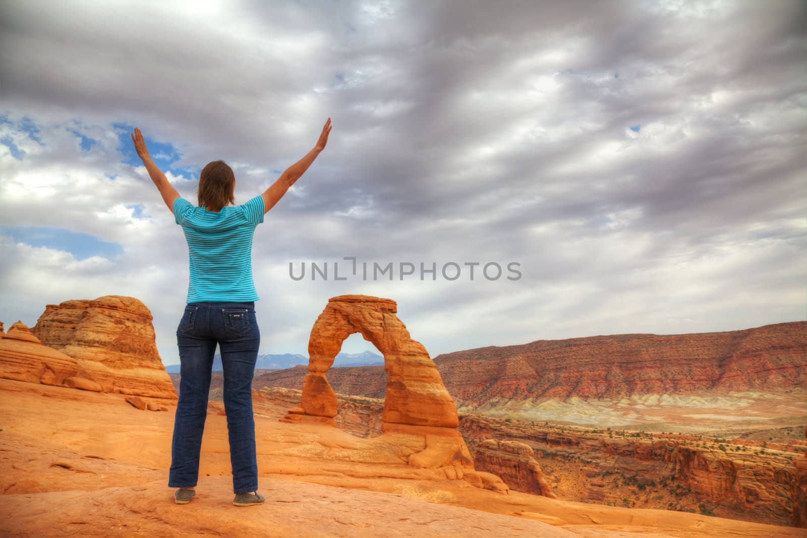 Woman with raised hands staying in front of Delicate Arch, Utah