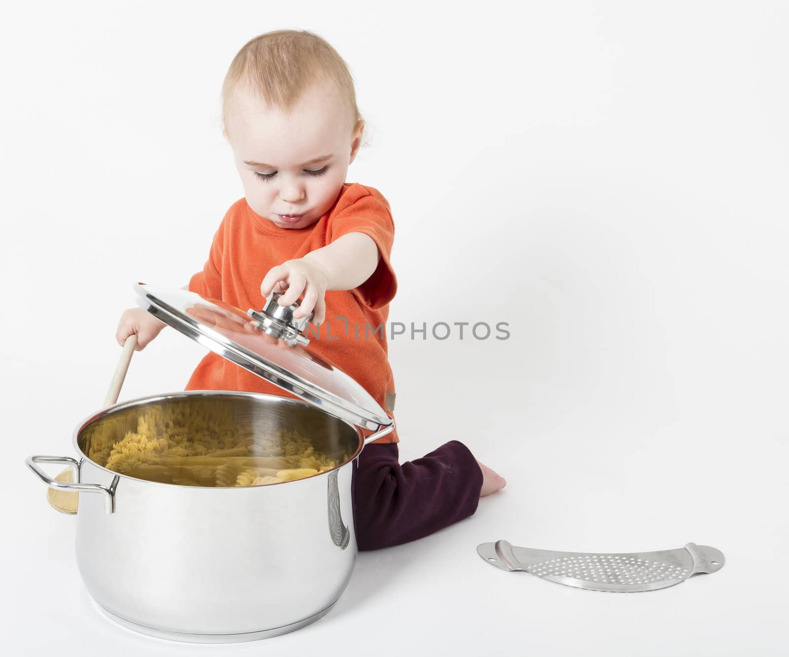 baby with big cooking pot in neutral grey background