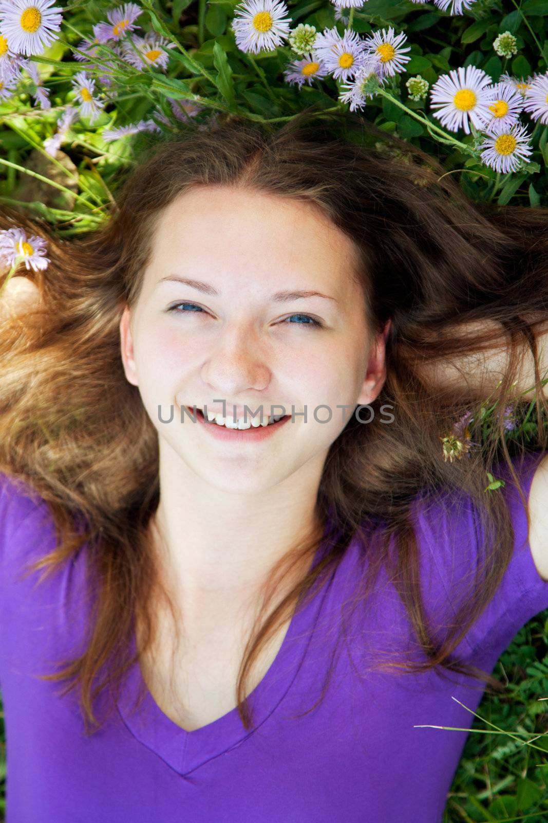 Teen girl lying in grass with flowers